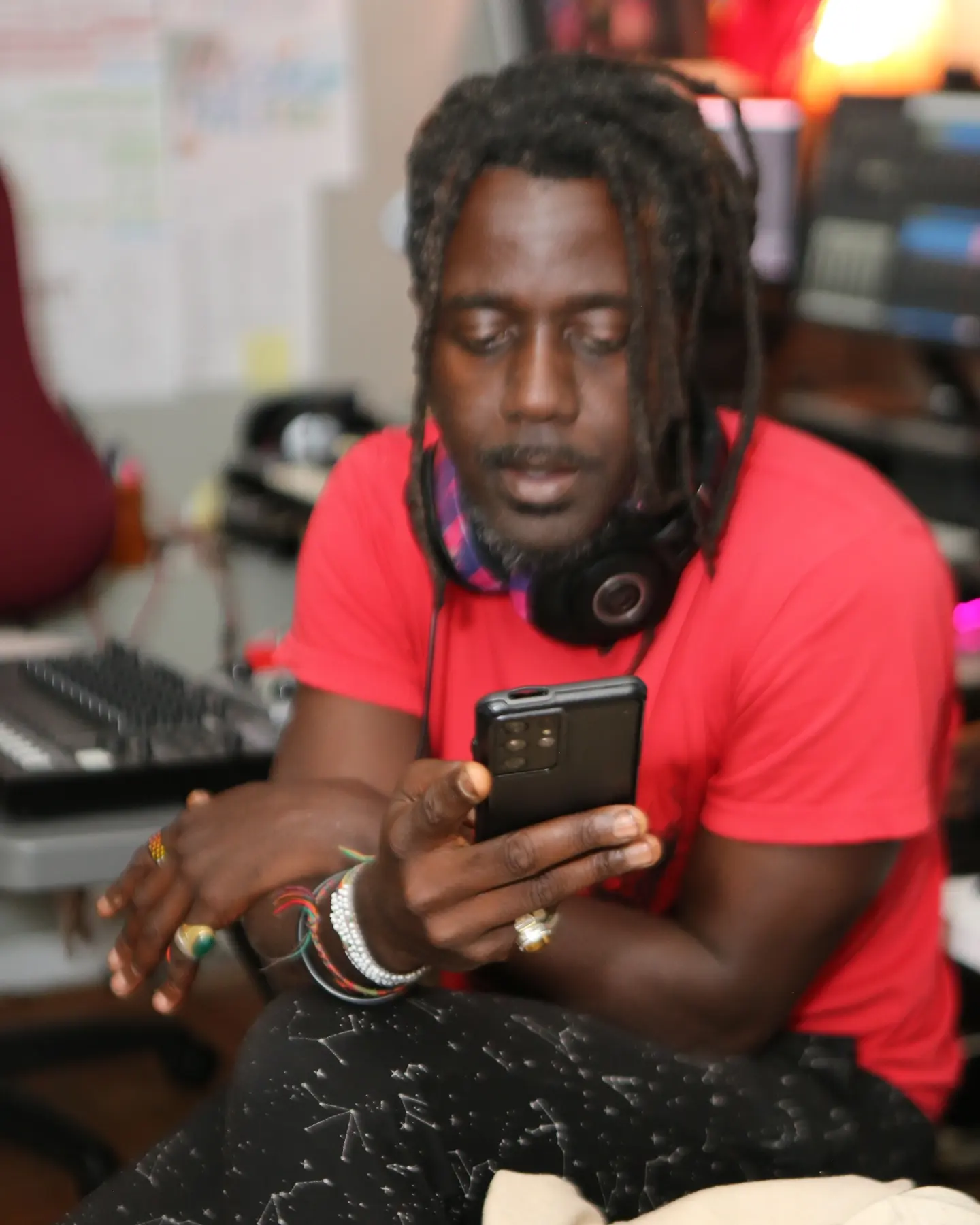 AshEL in the studio holding a phone, headphones nearby