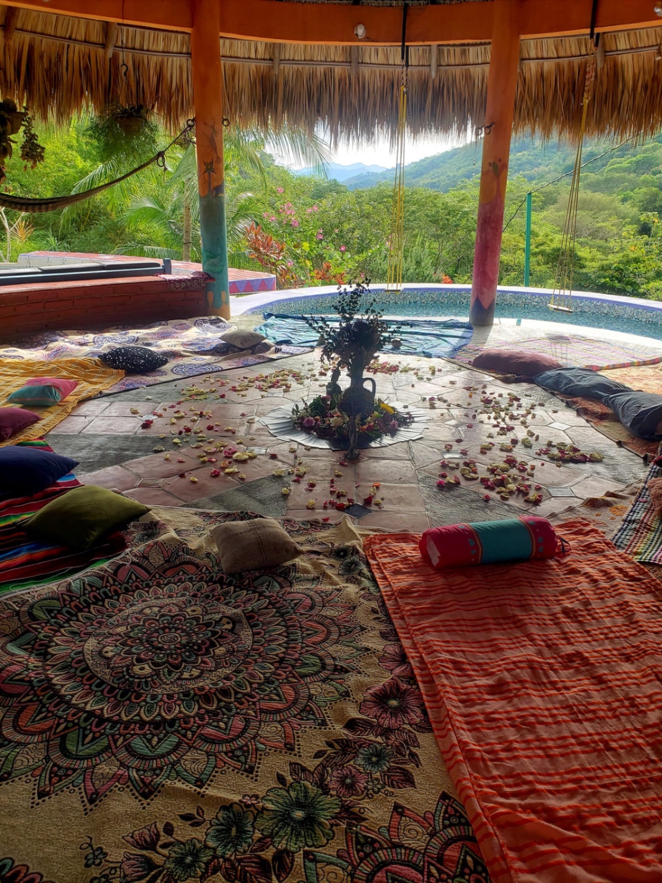 A community gathered in a ceremonial circle under a palapa at dusk