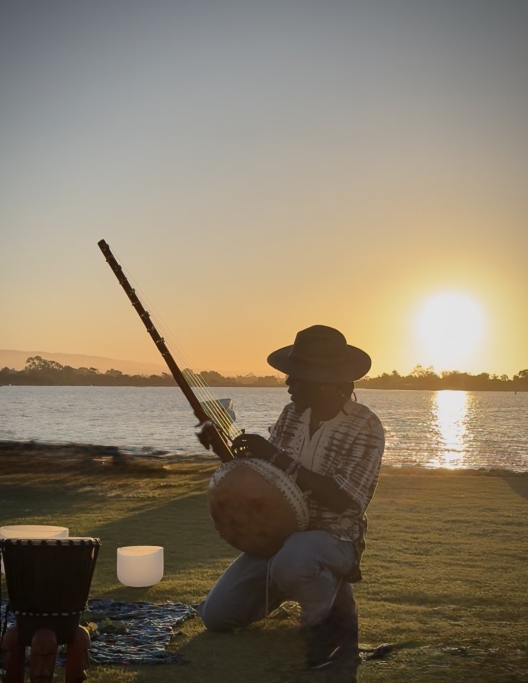 AshEL playing ngoni at sunset over water